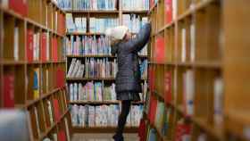 Una niña cogiendo un libro en una biblioteca