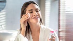Una mujer se limpia la cara con agua micelar.