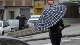 Una persona se cubre de la lluvia con un paraguas. Imagen de archivo