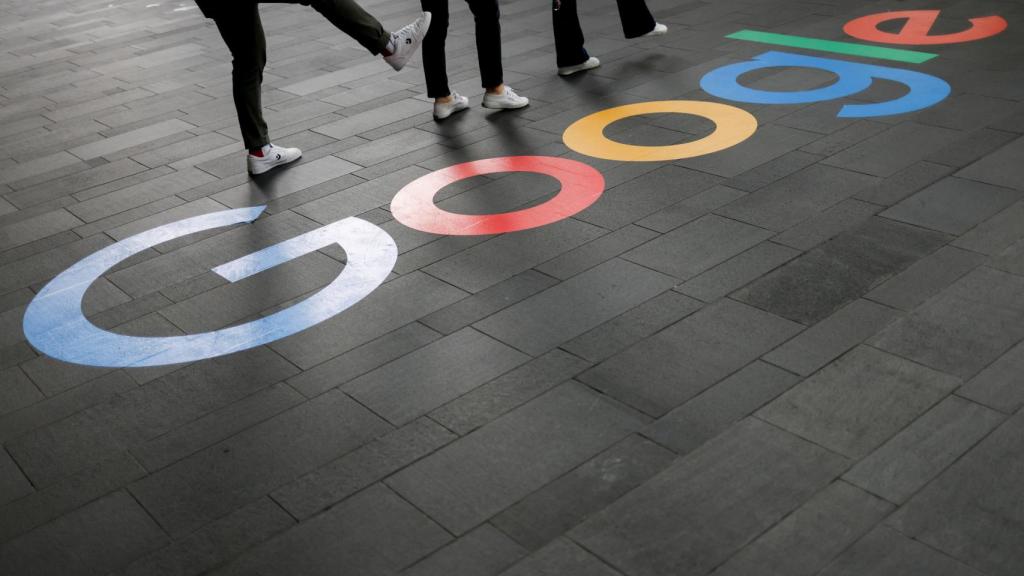 Varias personas de pie junto al logotipo de Google fuera de las oficinas de la empresa en Singapur.