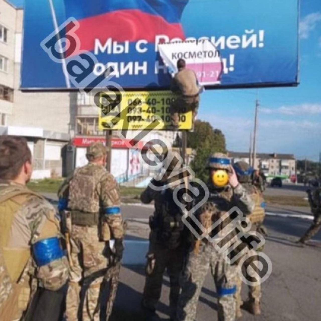 A Ukrainian soldier tears down a poster with Russian propaganda in the city of Balakliya.