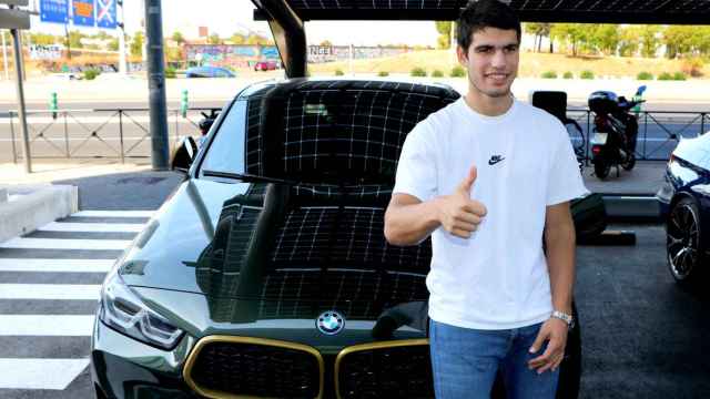Carlos Alcaraz junto con un coche electrificado de la gama BMW.