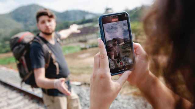 Una persona haciendo una foto con su smartphone a un joven en una montaña.