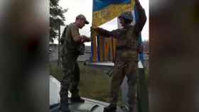 Dos soldados ucranianos celebran la retirada de las tropas rusas de Limán desplegando una bandera de su país.