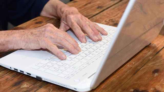 Imagen de archivo de las manos de una anciana utilizando un ordenador.
