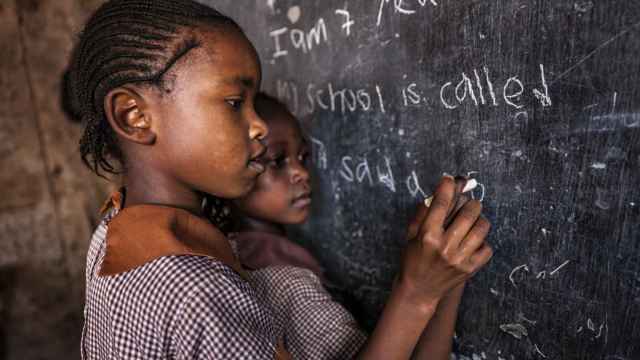 Imagen de niñas en escuela escribiendo en la pizarra