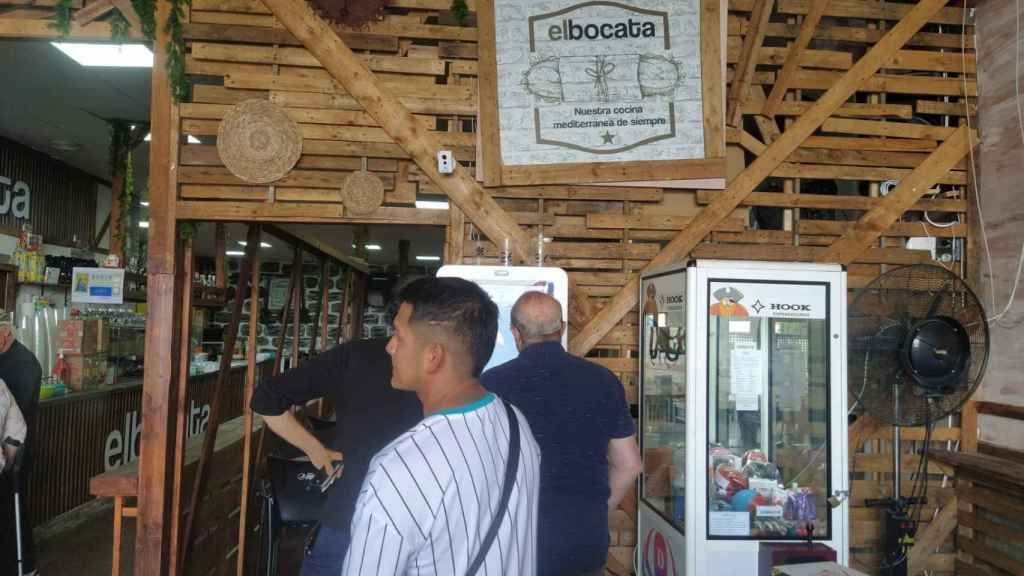 Una cola de clientes de El Bocata, esperando su turno para el pedir en la máquina su menú del día.
