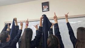 Un grupo de colegialas realiza cortes de manga a los retratos de los ayatolás Jamenei y Jomenei.