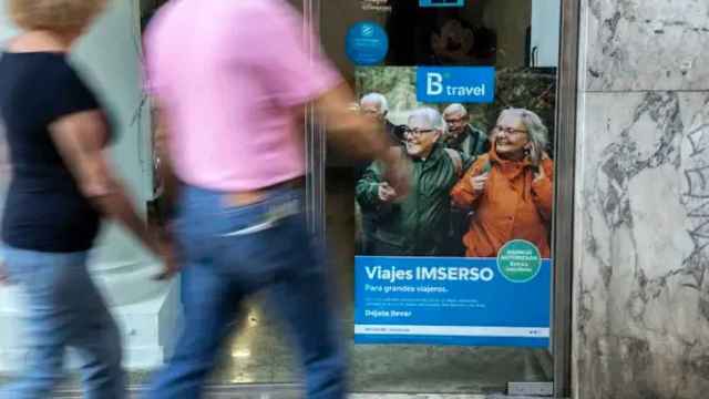 Dos personas pasan por delante de una oficina en Valencia que oferta viajes del Imserso.