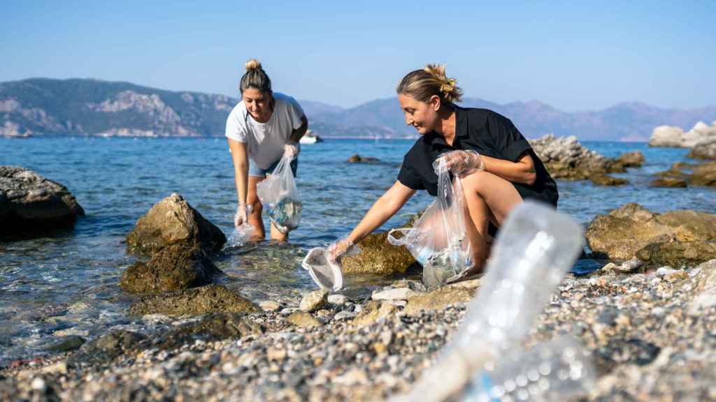 Dos voluntarias recogen residuos de plástico en una playa