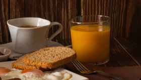 Un desayuno con café, zumo y tostadas con huevos.