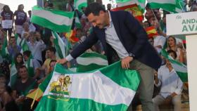 El presidente de la Junta, Juanma Moreno, coge una bandera andaluza durante el primer acto de campaña del pasado 19 de junio.