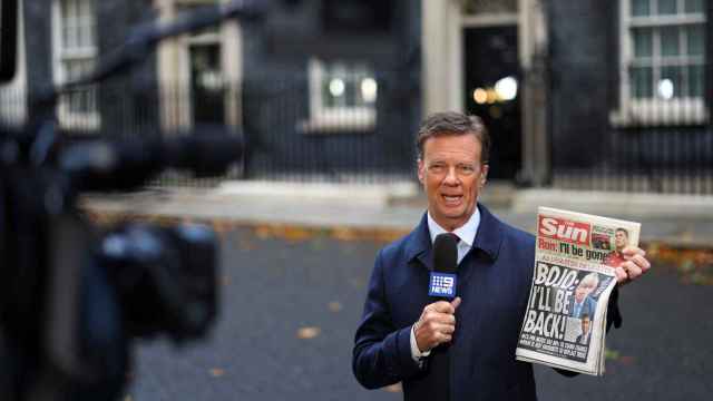 Un periodista con una copia de The Sun que adelanta la vuelta de Johnson, frente a Downing Street.