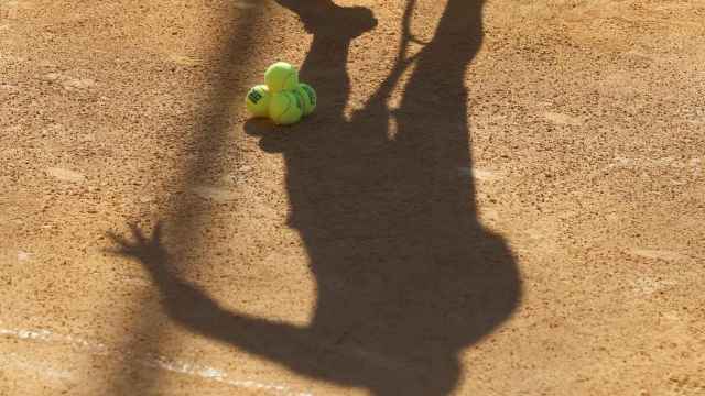 La silueta de un jugador proyectada sobre unas pelotas de tenis.