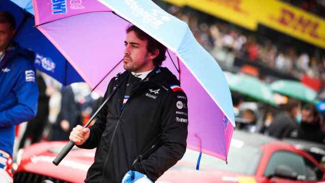 Fernando Alonso se resguarda de la lluvia con un paraguas