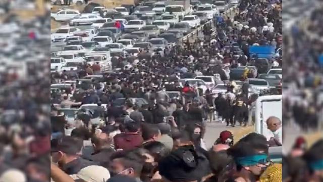 Iraníes caminan por la carretera hacia el cementerio donde se encuentran los restos de Mahsa Amini.