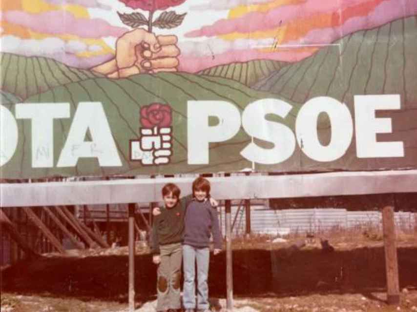 Daniel Sánchez Arévalo con su hermano, delante del cartel de su padre, el día que el PSOE gana las elecciones.