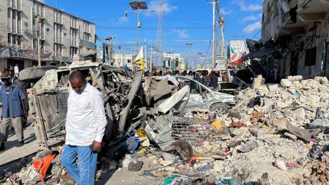Un hombre pasa junto a restos de vehículos destruidos cerca de las ruinas de un edificio