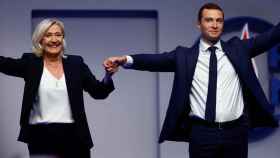 Jordan Bardella, nuevo presidente del partido de ultraderecha Agrupación Nacional, sostiene la mano de su predecesora, Marine Le Pen.