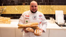 El maestro panadero Julio López, sujetando cinco panes elaborados y vendidos en Lidl.