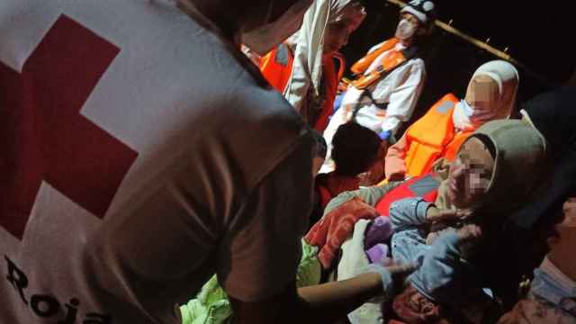 Una persona de Cruz Roja atiende a unos migrantes llegados en pateras, en imagen de archivo.