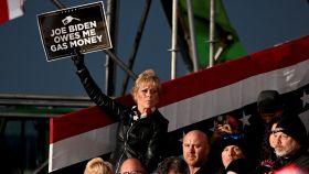 Una mujer sujeta el cartel Joe Biden me debe dinero para gasolina en un mitin de Trump.