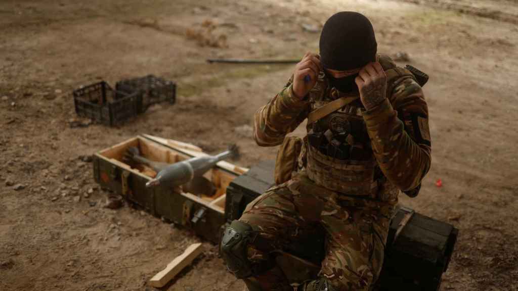Ukrainian soldiers sit on a Russian mortar shell seized in the village of Blahodatne, Kherson region
