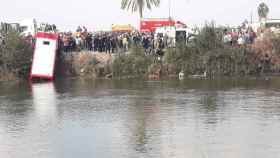 Los servicios de emergencia rescatan el autobús tras caer en el río Nilo este sábado.