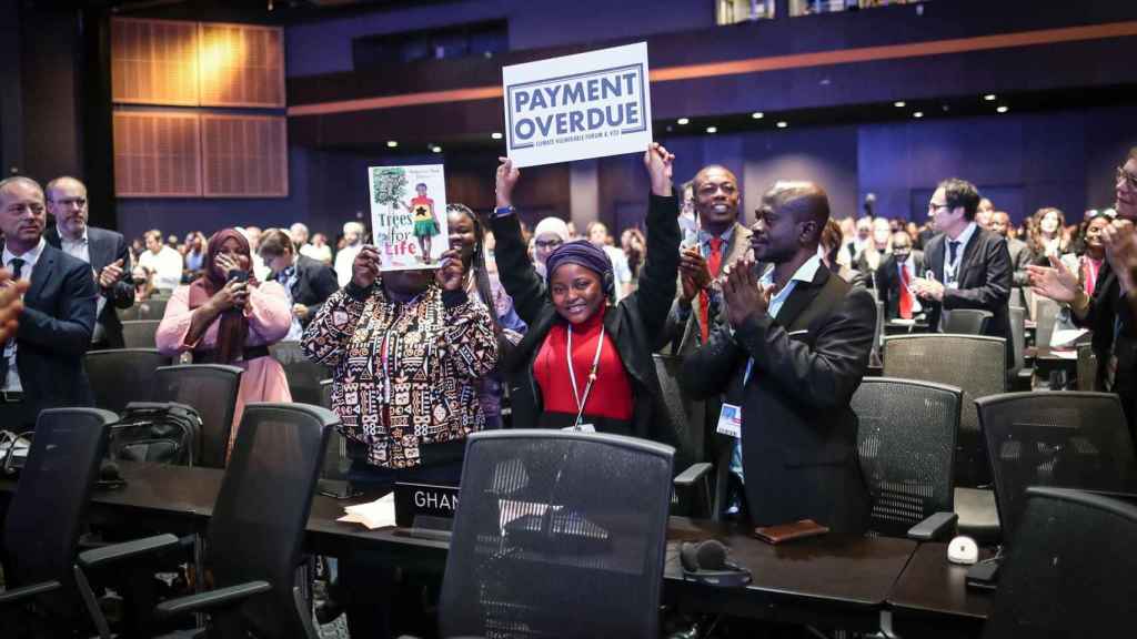 La poeta de Ghana Nakeeyat Sam Dramani sostiene una pancarta que reza 'pago vencido' durante una reunión en la COP27.
