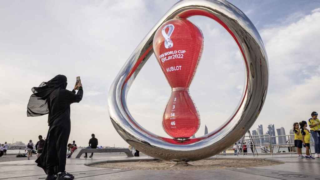 Una aficionada toma una fotografía en el reloj que marca la cuenta atrás para el inicio del Mundial de Qatar