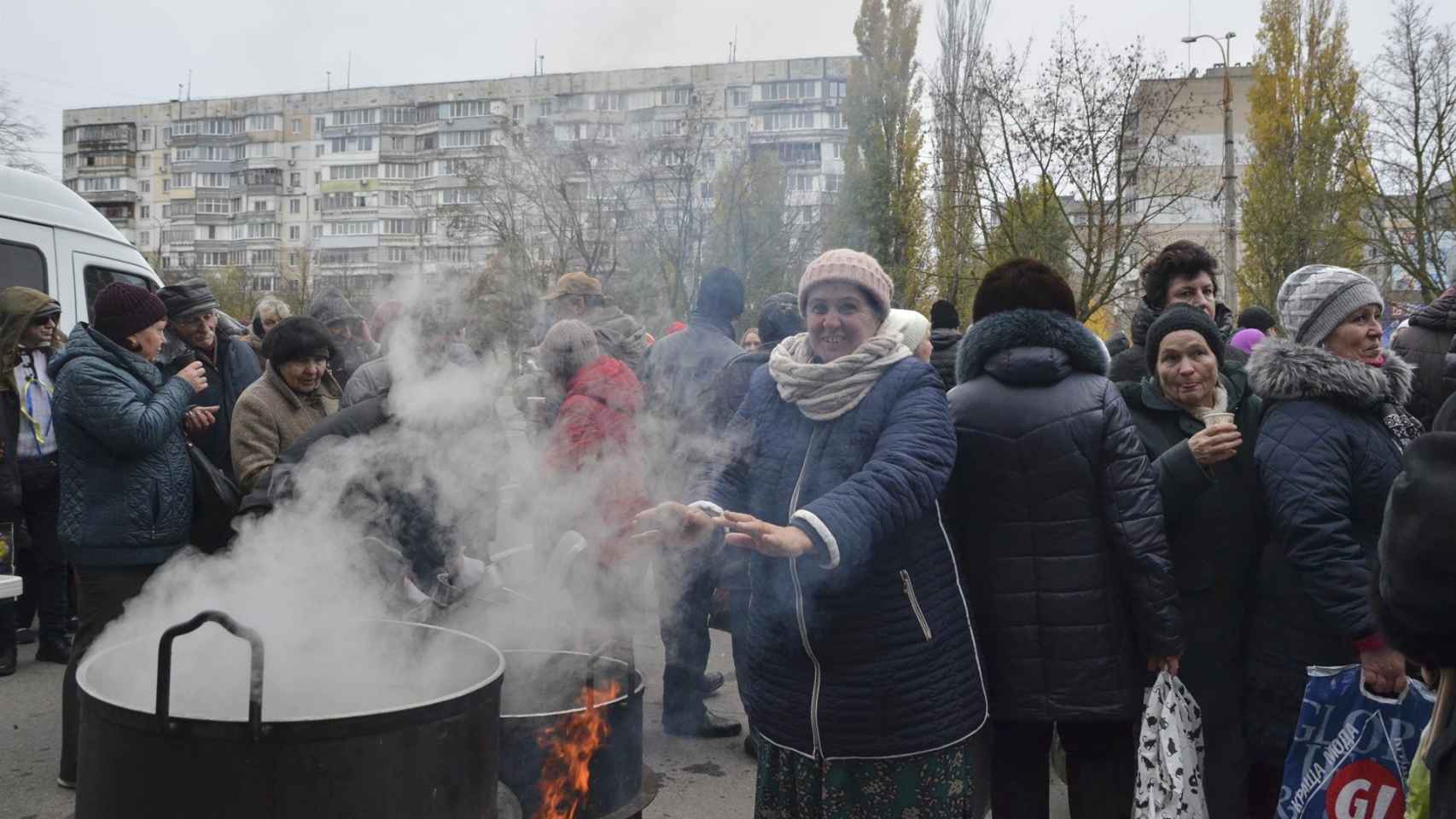 Una mujer local se calienta las manos mientras los voluntarios cocinan comida para los locales en Kherson, Ucrania, el 18 de noviembre de 2022.