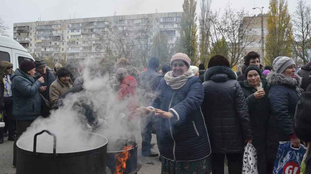 A local woman warms her hands as volunteers cook food for locals in Kherson, Ukraine on November 18, 2022.