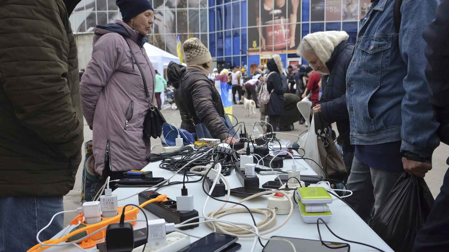 Vecinos cargan sus teléfonos móviles desde un generador en una calle de la ciudad de Kherson, Ucrania, el 18 de noviembre de 2022..