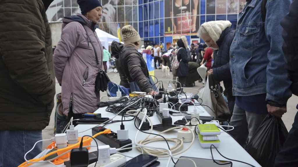 Neighbors charge their mobile phones from a generator on a street in the city of Kherson, Ukraine, on November 18, 2022.