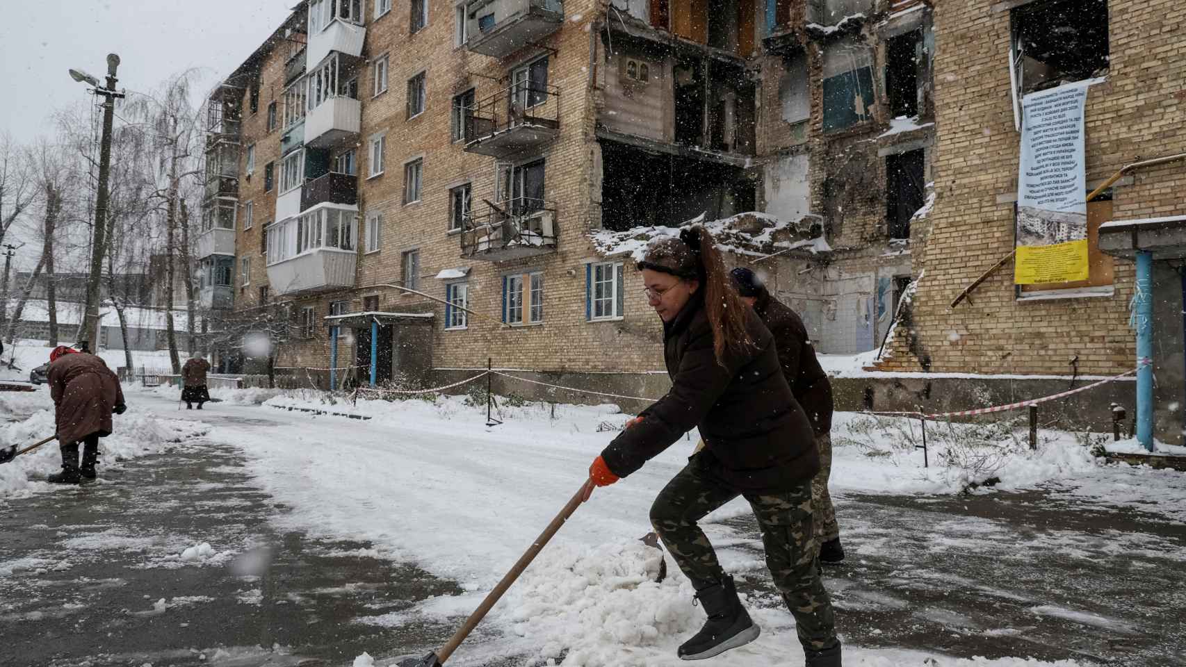 Tetiana Reznychenko, residente de la aldea ucraniana de Horenka, palea nieve cerca de su edificio de apartamentos, que no tiene electricidad, calefacción ni agua corriente.