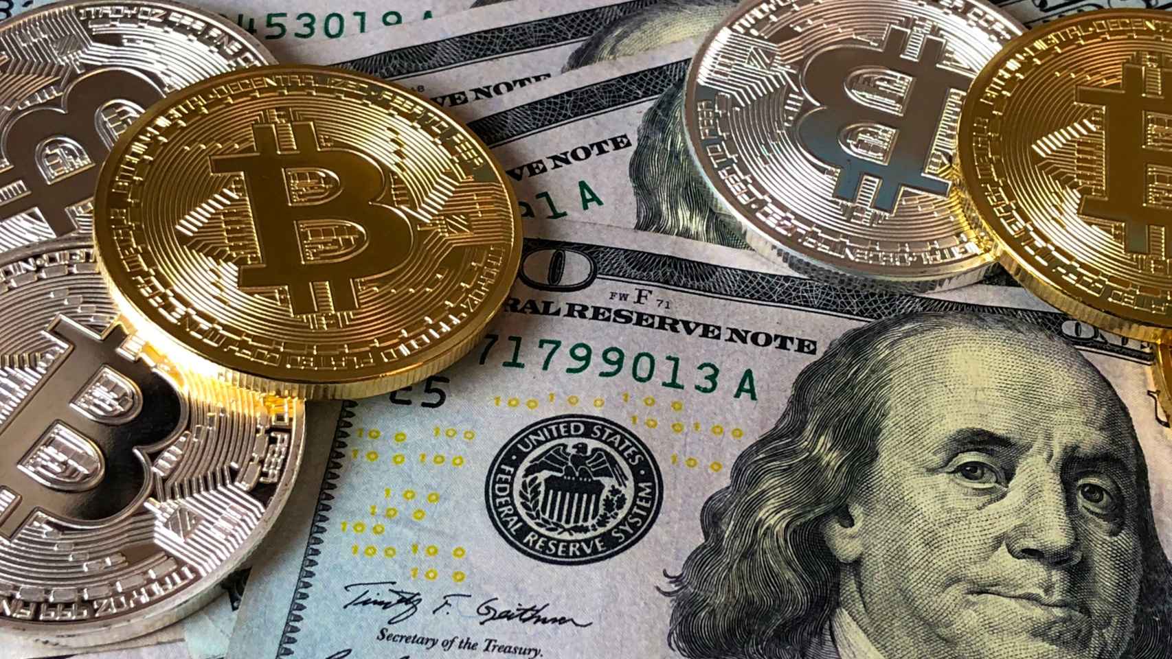 Monedas de bitcoin sobre billetes de dólar.