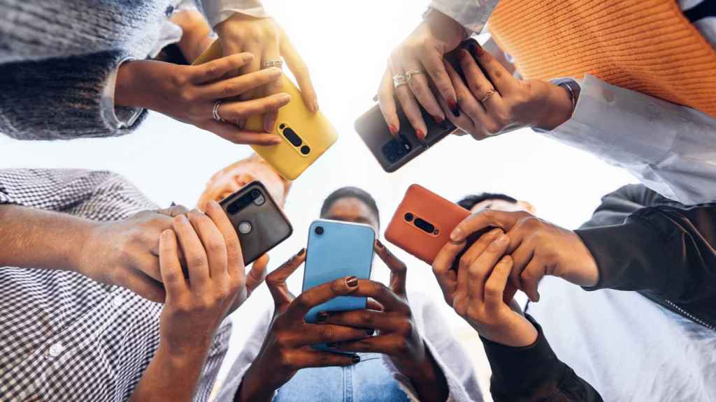 Fotografía de archivo de un grupo de personas que usan teléfonos móviles.