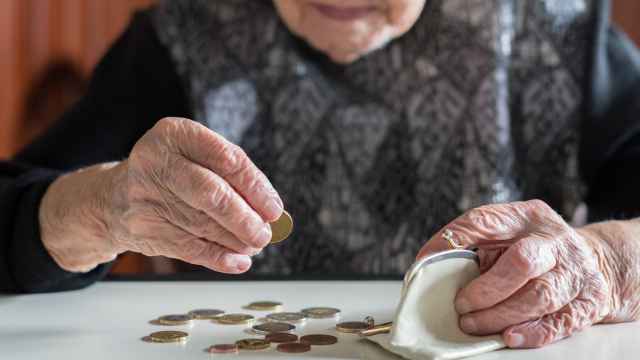 Una anciana cuenta las monedas de su monedero.