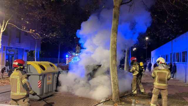 Los bomberos sofocan el fuego en un contenedor de papel en el barrio de Villa del Prado