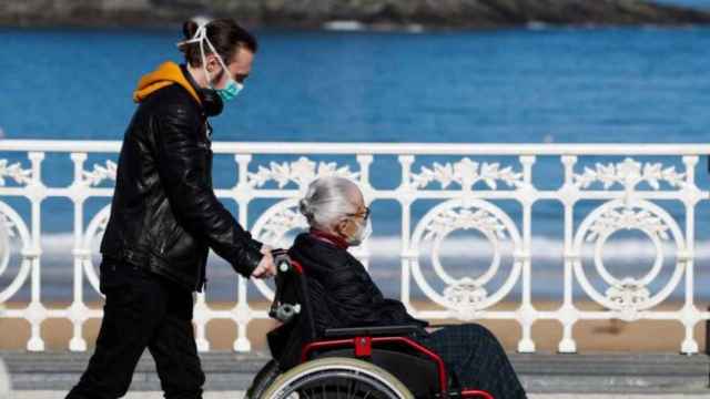 Un hombre lleva a una anciana en silla de ruedas, en imagen de archivo.