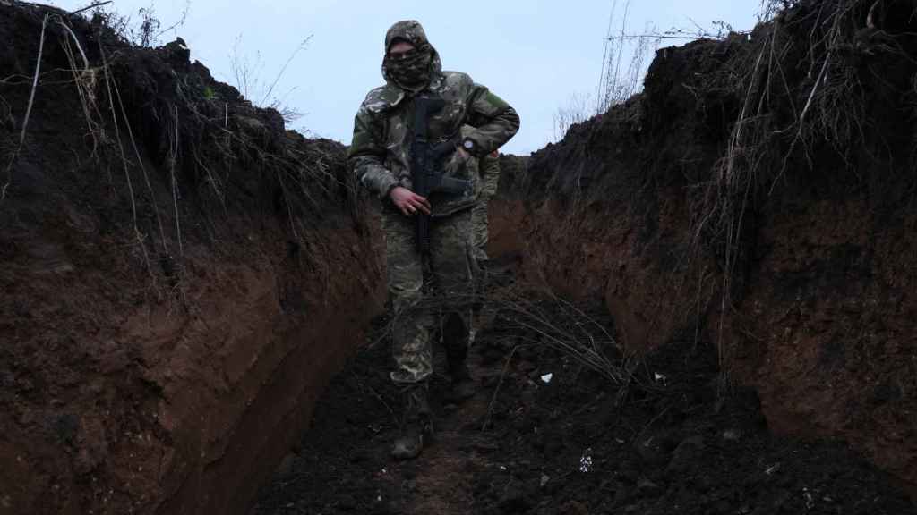 Un soldado ucraniano armado recorre una trinchera.
