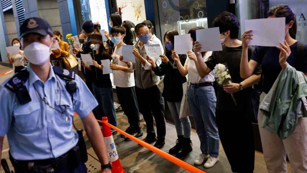Una fila de jóvenes tapan su rostro con papeles blancos como señal de protesta ante la presencia de los agentes chinos.