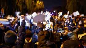 Manifestantes agitan papeles en blanco durante una protesta en Urumqi, en China.