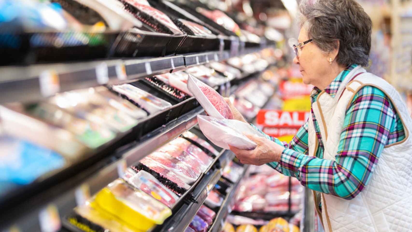 Una mujer revisa los precios de los productos en un supermercado.