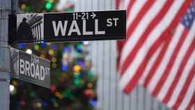 Una señal de Wall Street delante de un árbol de Navidad.