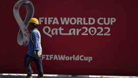 Un obrero pasa por delante de un cartel de Mundial de Qatar 2022 en Doha
