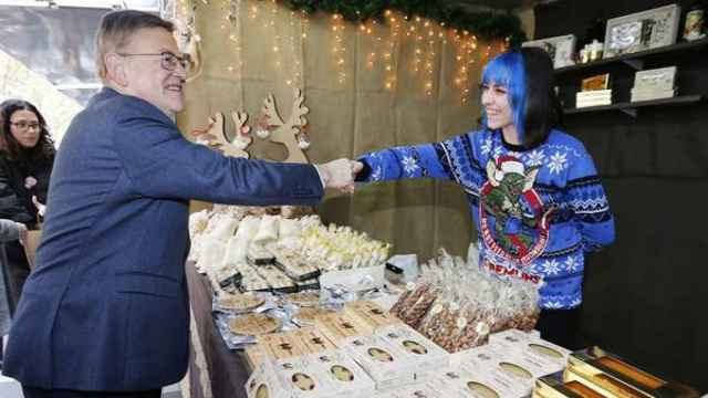 El president de la Generalitat Valenciana, Ximo Puig, saluda a una turronera durante la inauguración de la XIII Feria de Navidad de Xixona.