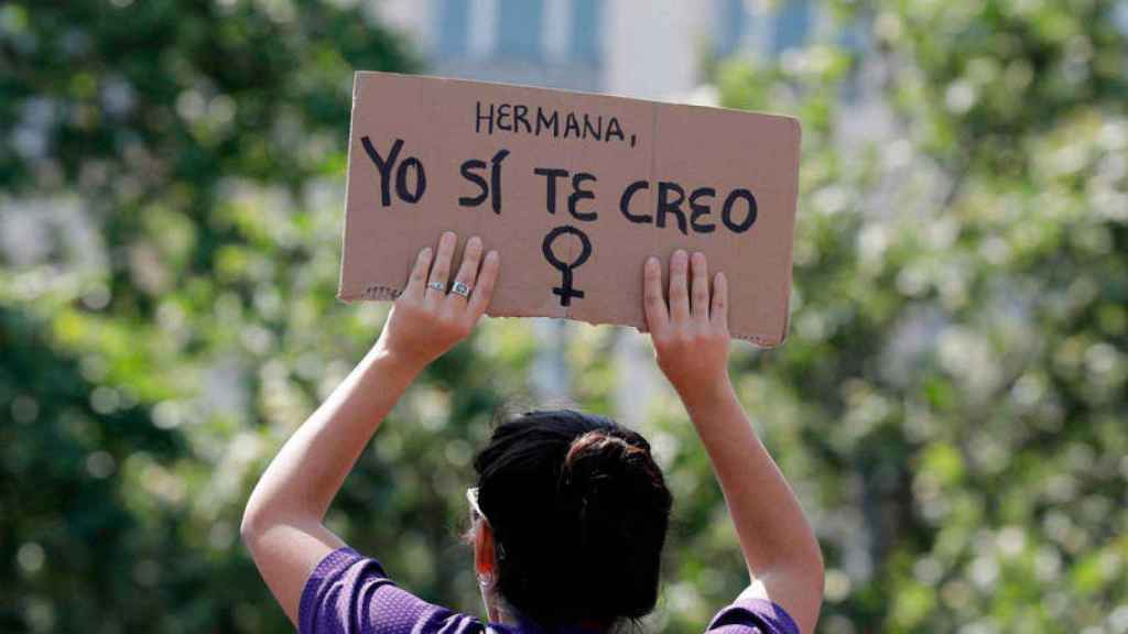 Una mujer sostiene una pancarta en una manifestación.