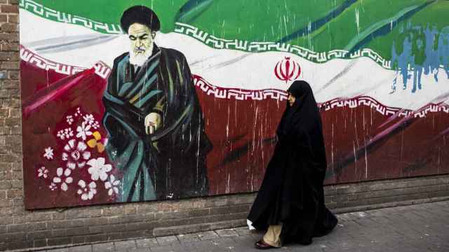 Una mujer junto a un mural con la bandera iraní y el ayatolá Ruholá Jomeini en Teherán.