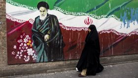 Una mujer junto a un mural con la bandera iraní y el ayatolá Ruholá Jomeini en Teherán.